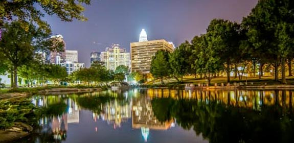 Charlotte, North Carolina, reflected in a tree-rimmed lake at nighttime
